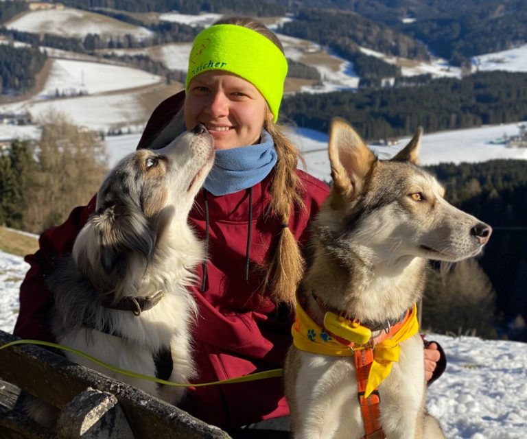 Sophia Hilsenbeck - Pfotensicher Junge Frau mit floralem Haarband und lächelndem Gesicht vor einer grünen Wand.
